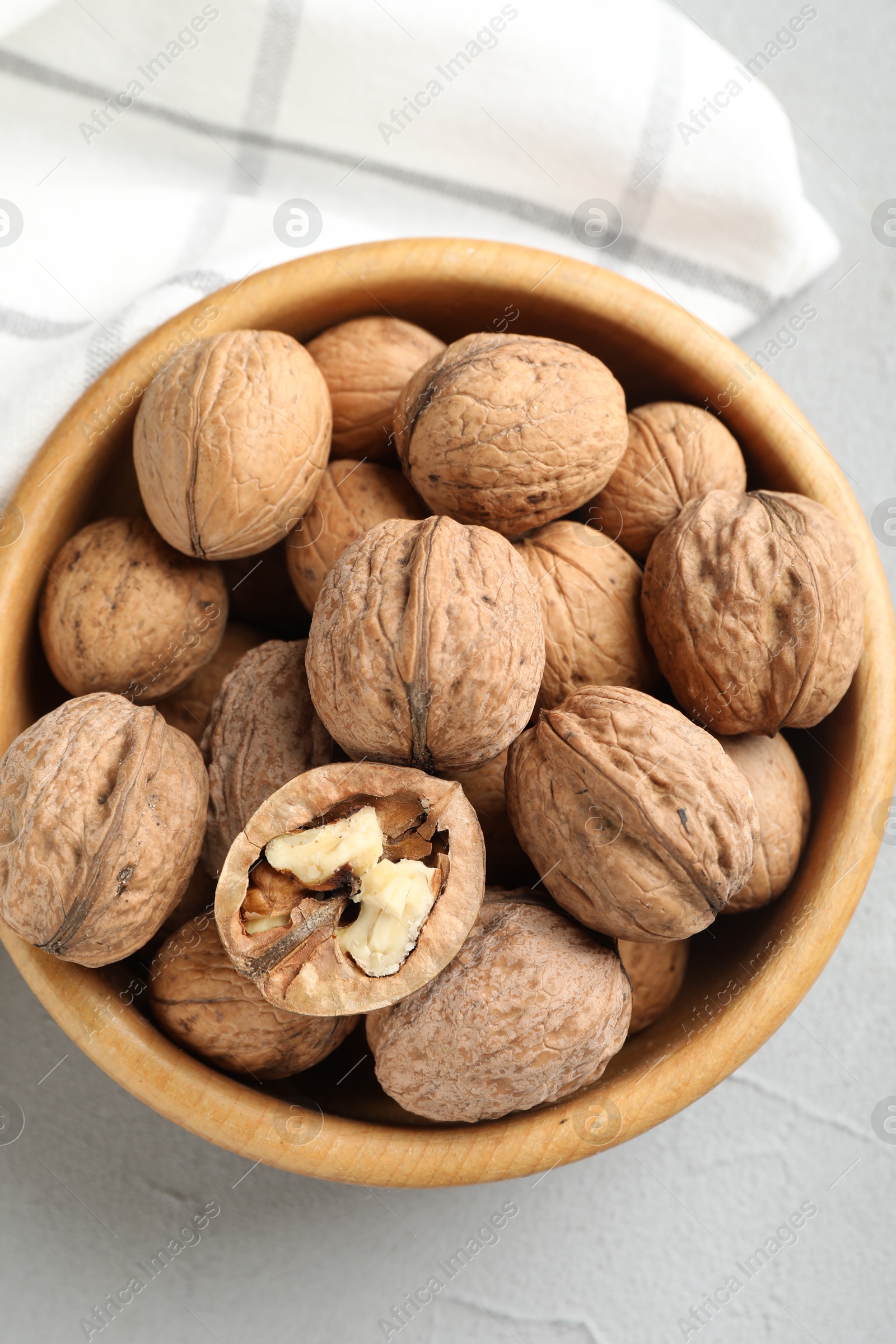 Photo of Fresh walnuts in bowl on gray table, top view