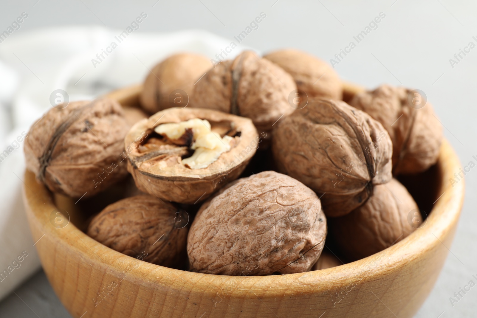 Photo of Fresh walnuts in bowl on gray table, closeup