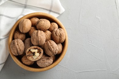 Photo of Fresh walnuts in bowl on gray table, top view. Space for text