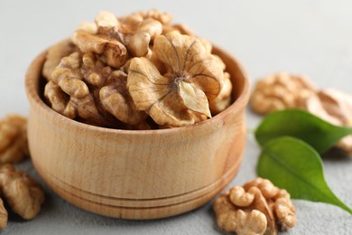 Photo of Peeled walnuts in bowl on gray table, closeup