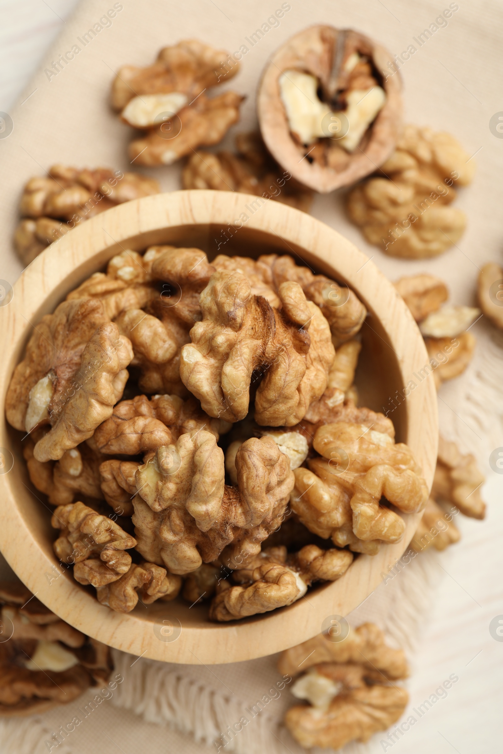 Photo of Peeled walnuts in bowl on light table, top view