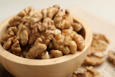 Photo of Peeled walnuts in bowl on light table, closeup