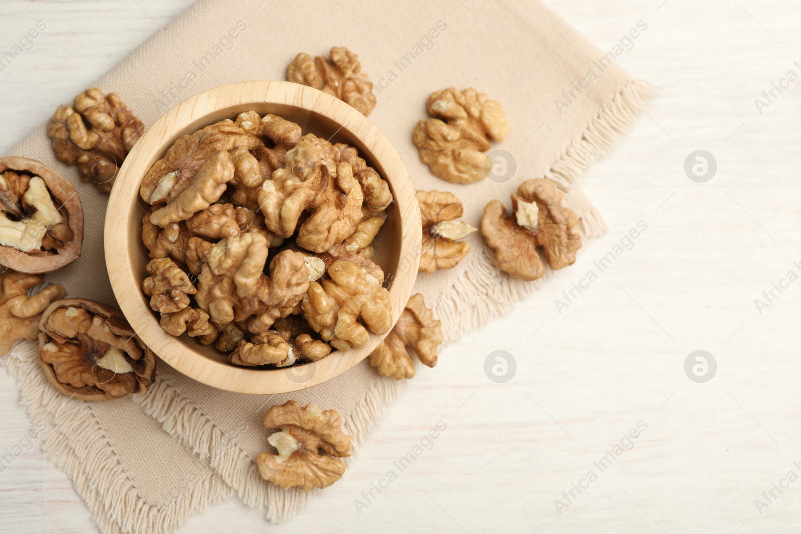 Photo of Peeled walnuts in bowl on light table, flat lay. Space for text