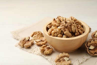 Photo of Peeled walnuts in bowl on light table, closeup. Space for text