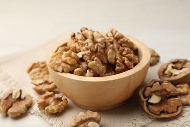 Photo of Peeled walnuts in bowl on light table, closeup