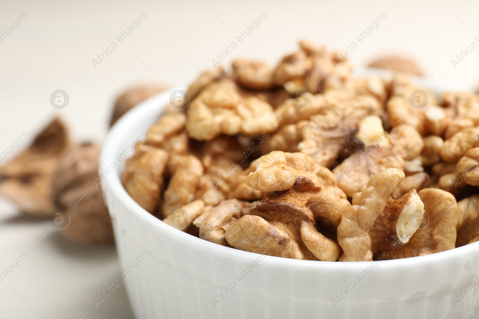 Photo of Peeled walnuts in bowl on light table, closeup