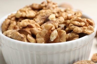 Photo of Peeled walnuts in bowl on light table, closeup