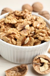 Photo of Peeled walnuts in bowl on light table, closeup