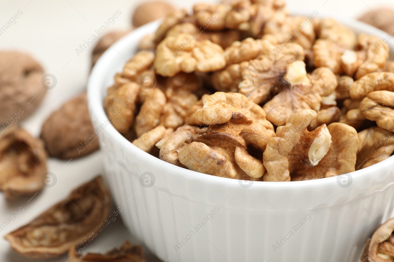 Photo of Peeled walnuts in bowl on light table, closeup