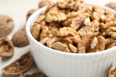 Photo of Peeled walnuts in bowl on light table, closeup