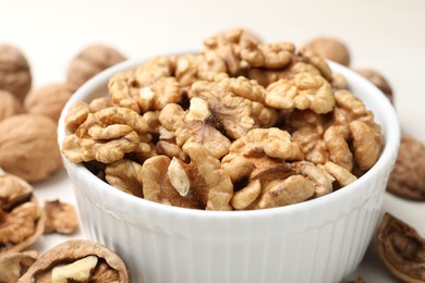 Photo of Peeled walnuts in bowl on light table, closeup