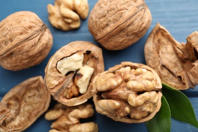 Photo of Fresh walnuts with shells on blue table, flat lay