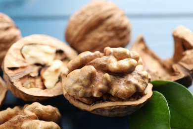 Photo of Fresh walnuts with shells on blue table, closeup