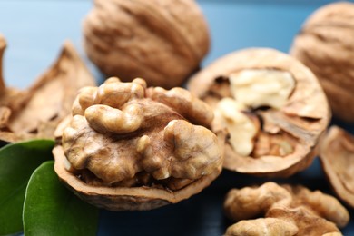 Photo of Fresh walnuts with shells on blue table, closeup