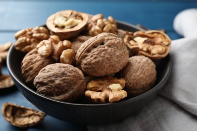 Photo of Fresh walnuts in bowl on blue table, closeup