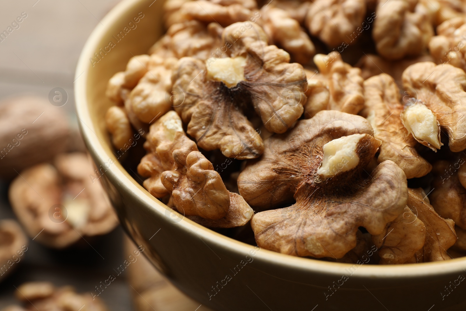 Photo of Peeled walnuts in bowl on table, closeup