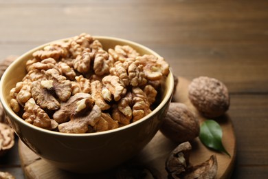 Photo of Peeled walnuts in bowl on table, closeup. Space for text