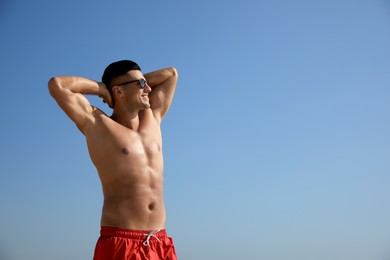 Photo of Handsome man with attractive body against blue sky. Space for text