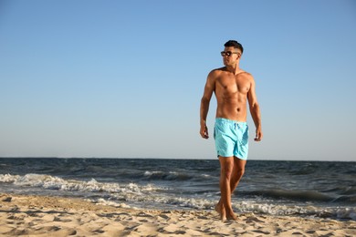 Photo of Handsome man with attractive body on beach. Space for text