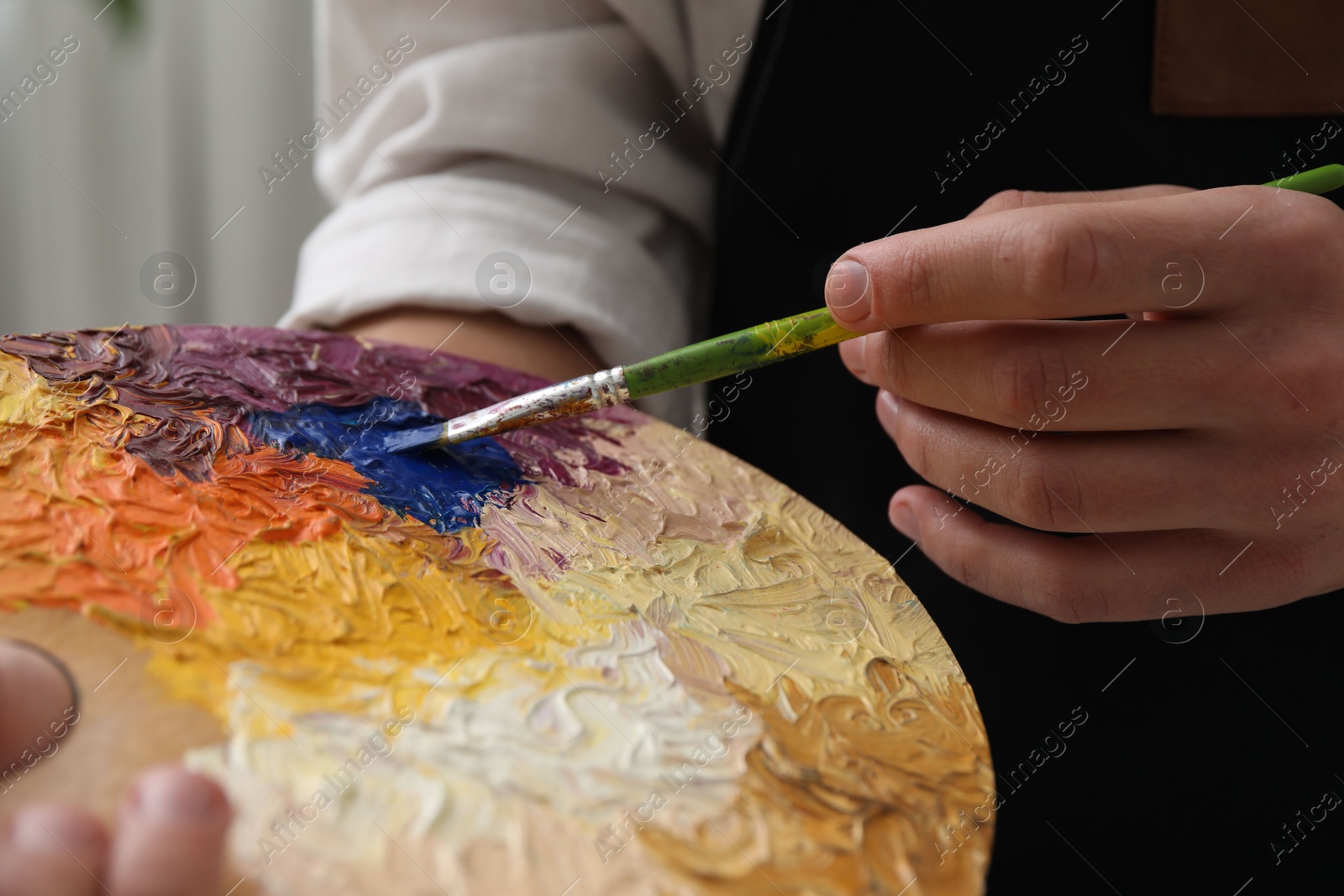 Photo of Man with palette and paintbrush indoors, closeup