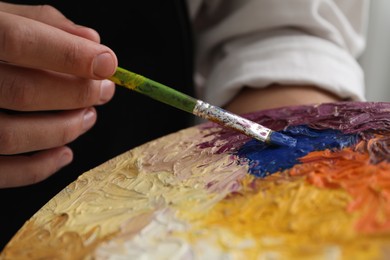 Photo of Man painting with palette and paintbrush, closeup