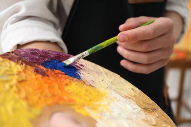 Photo of Man with palette and paintbrush indoors, closeup