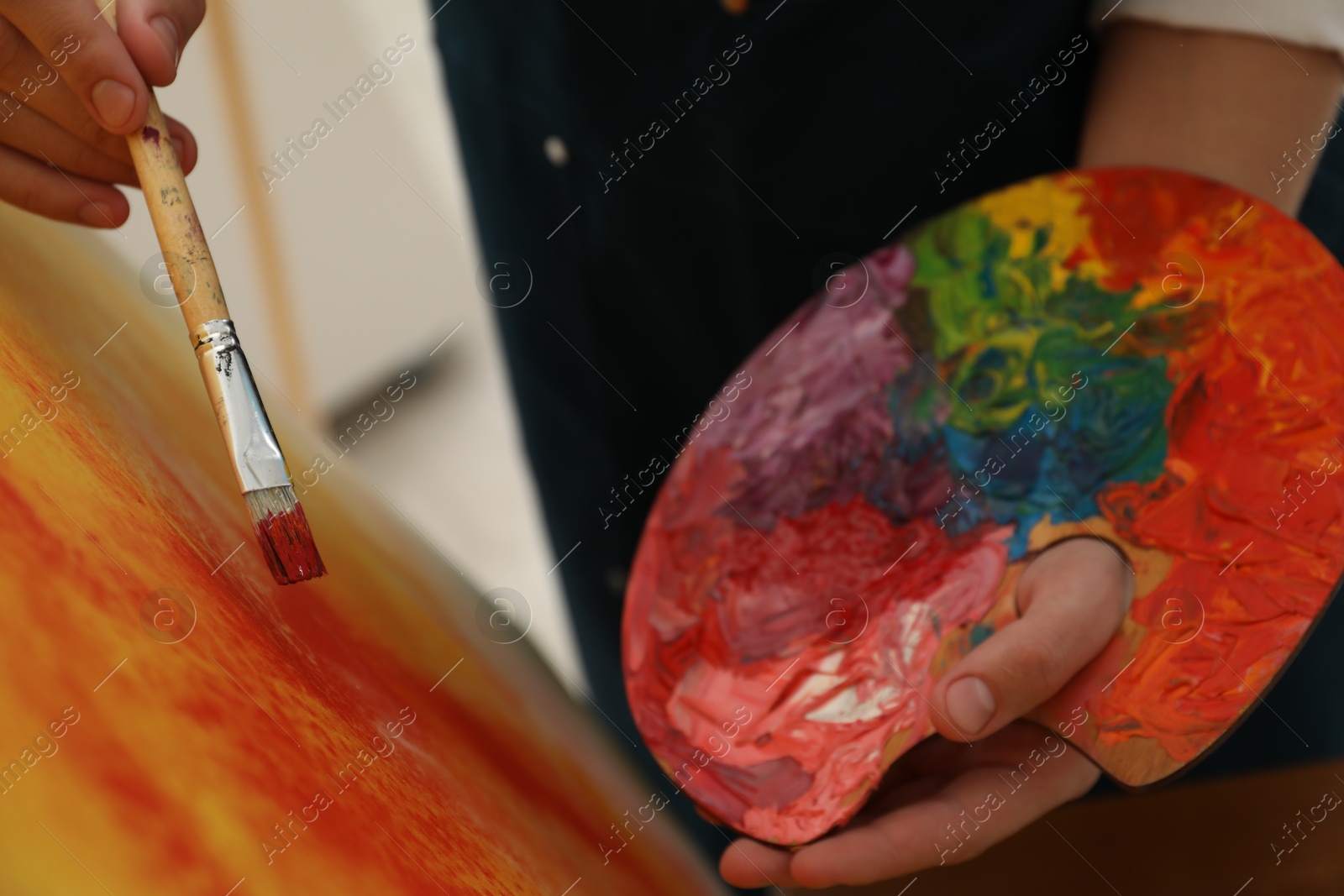 Photo of Man with palette and paintbrush drawing picture indoors, closeup