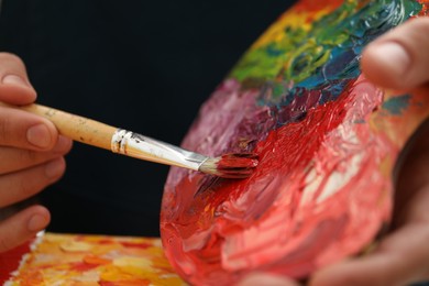 Photo of Man with palette and paintbrush drawing picture, closeup