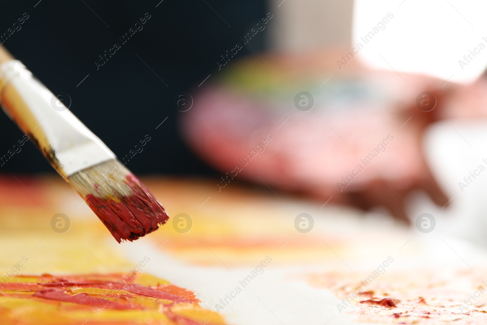 Photo of Drawing picture with paintbrush on blurred background, closeup