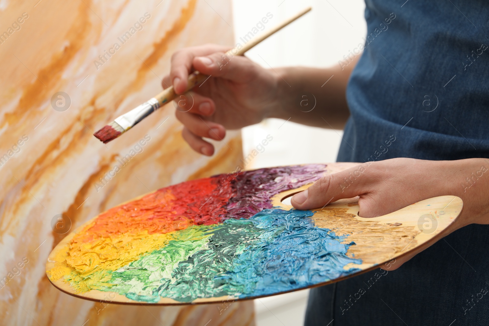 Photo of Man with palette and paintbrush drawing picture, closeup