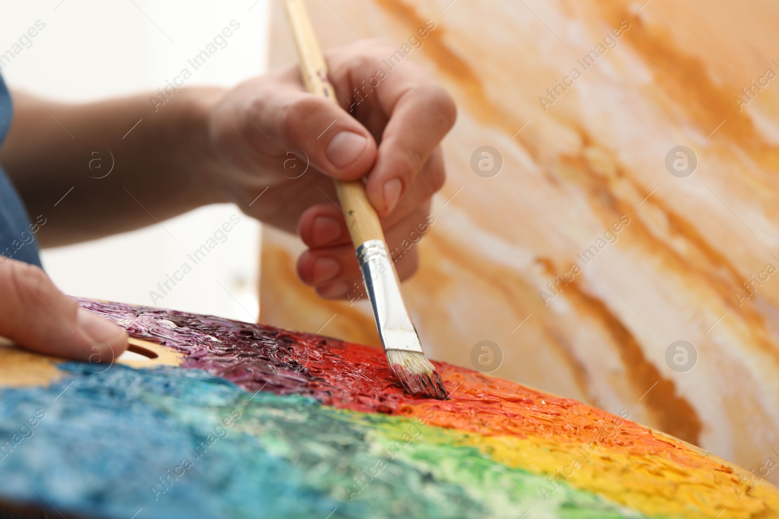 Photo of Man with palette and paintbrush drawing picture, closeup