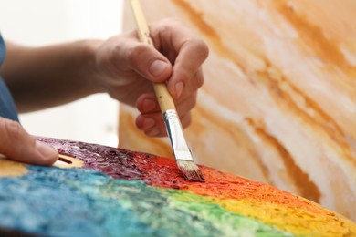 Photo of Man with palette and paintbrush drawing picture, closeup