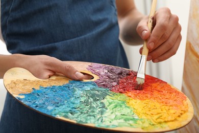 Photo of Man with palette and paintbrush drawing picture, closeup