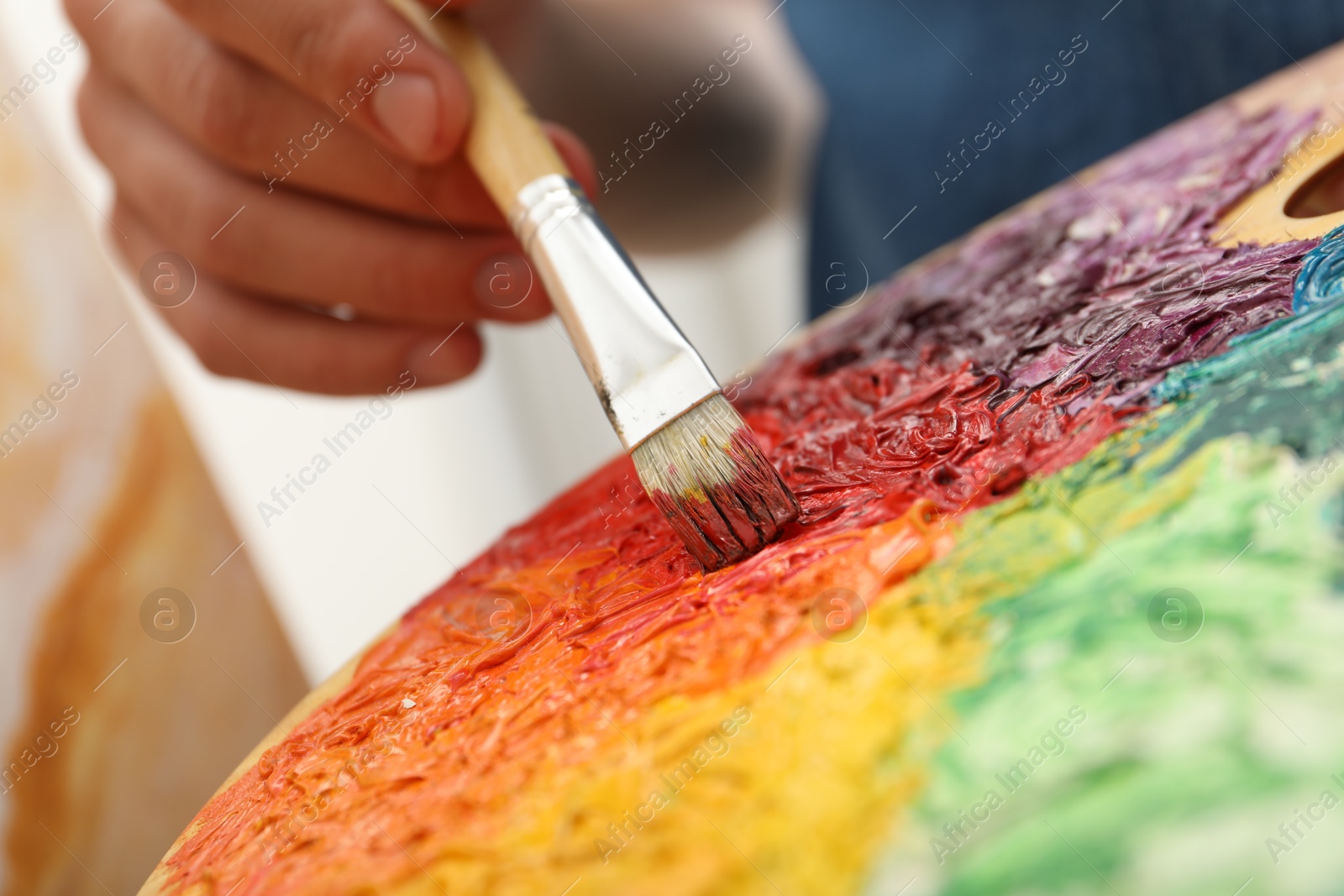 Photo of Man with palette and paintbrush drawing picture, closeup