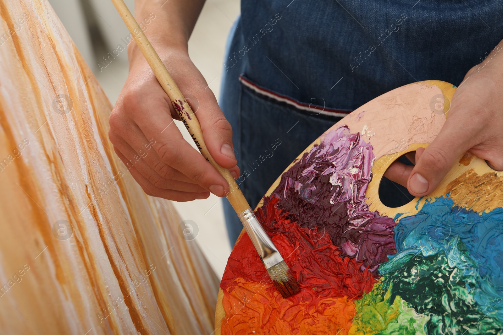 Photo of Man with palette and paintbrush drawing picture, closeup