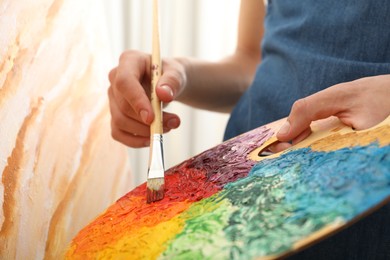 Man with paintbrush mixing paints on palette, closeup