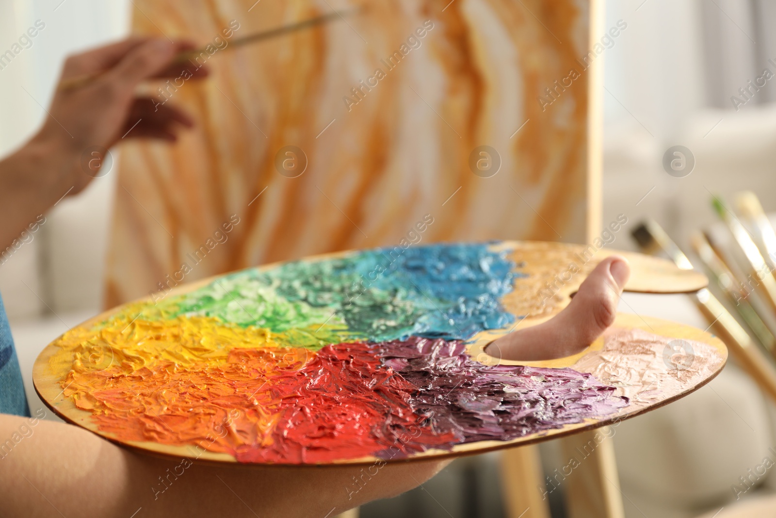 Photo of Man with palette drawing picture indoors, selective focus