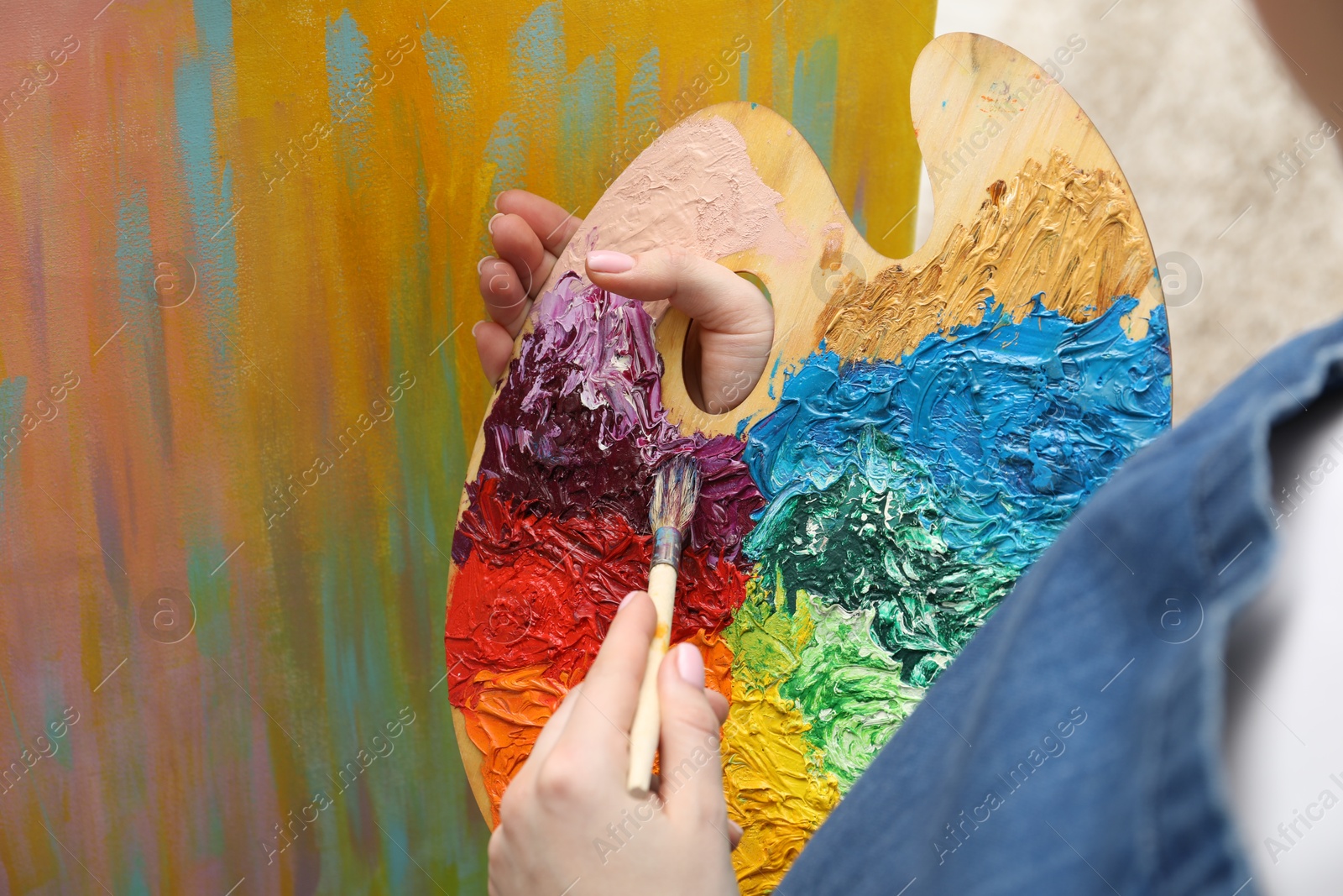 Photo of Woman with palette and paintbrush drawing abstract picture, closeup