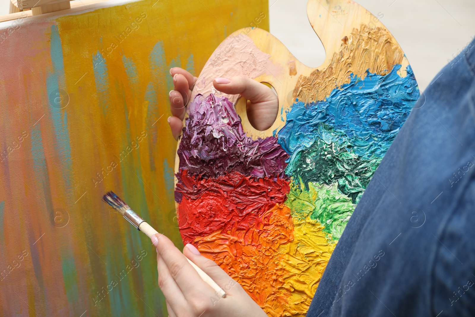 Photo of Woman with palette and paintbrush drawing abstract picture, closeup