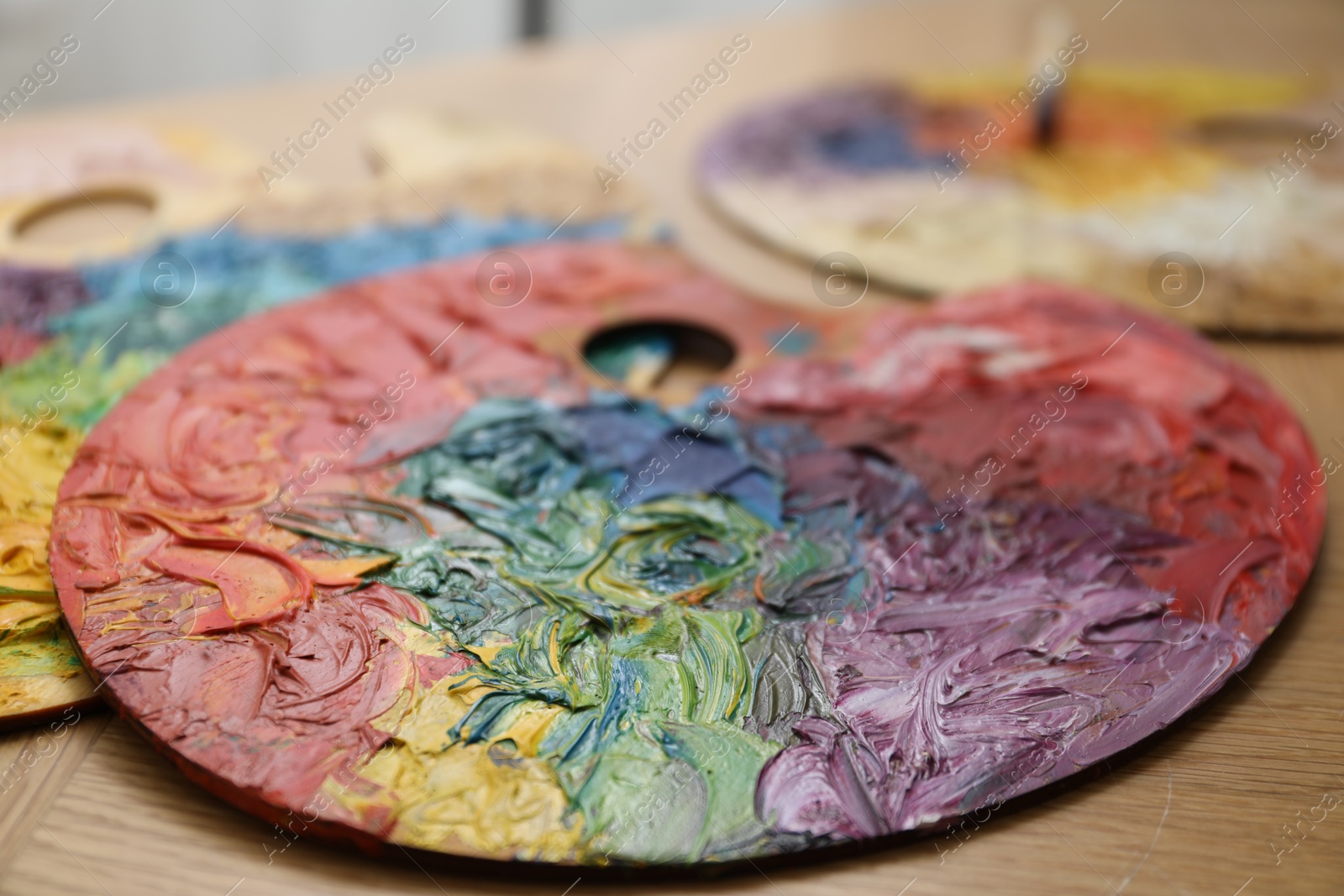 Photo of Palettes with bright paints on wooden table, closeup