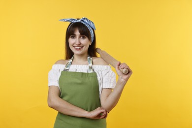 Photo of Happy woman with rolling pin on yellow background