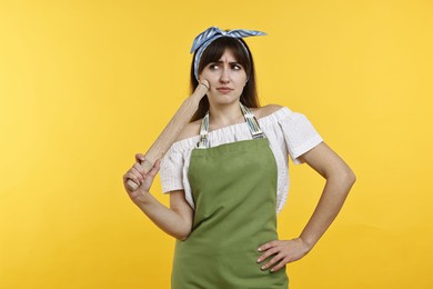 Photo of Confused woman with rolling pin on yellow background