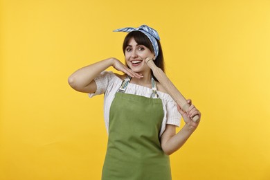 Photo of Happy woman with rolling pin on yellow background