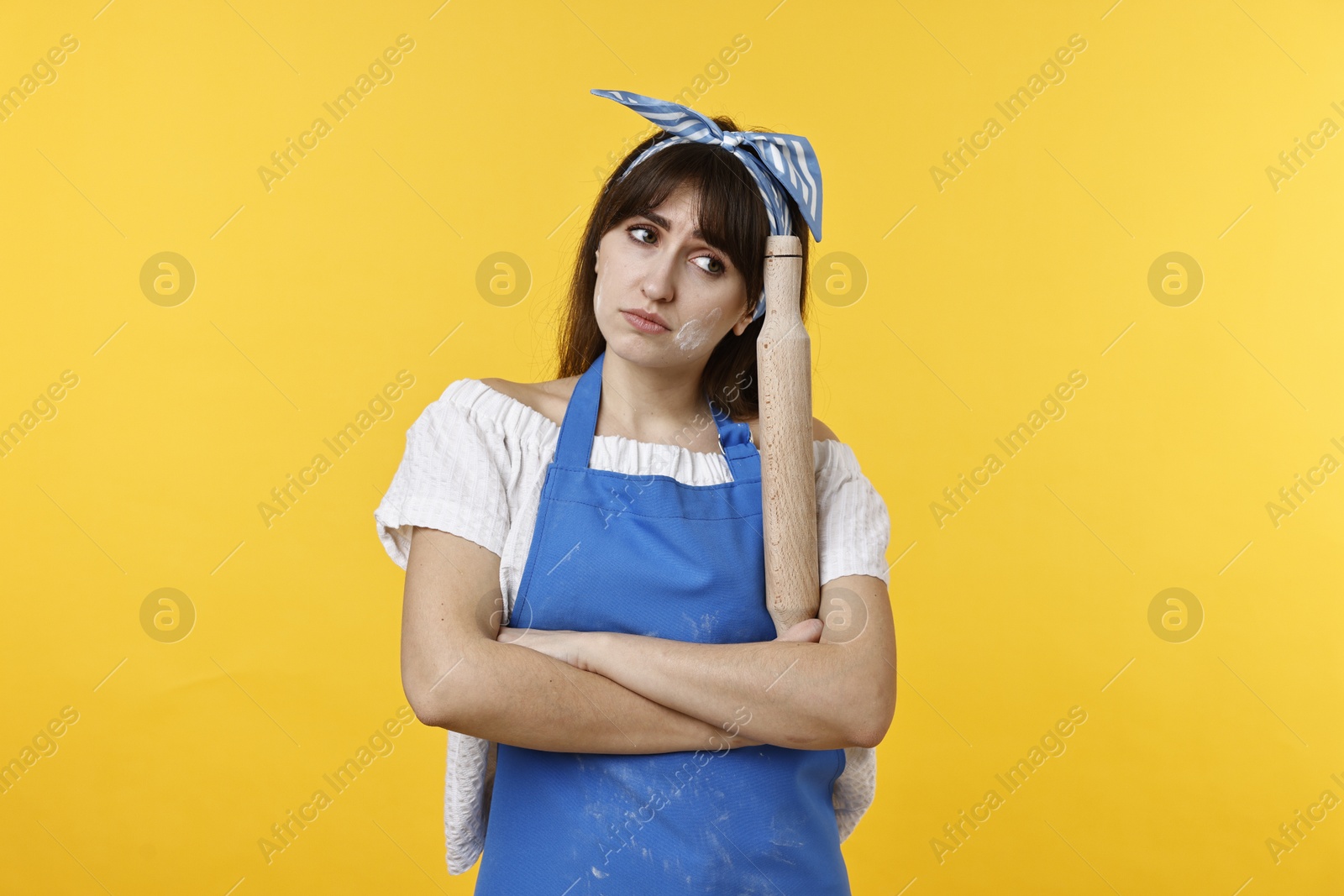 Photo of Upset woman with rolling pin on yellow background