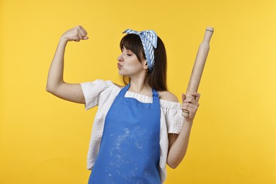 Photo of Woman with rolling pin kissing bicep on yellow background