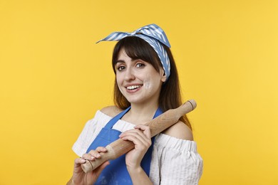 Photo of Happy woman with rolling pin on yellow background