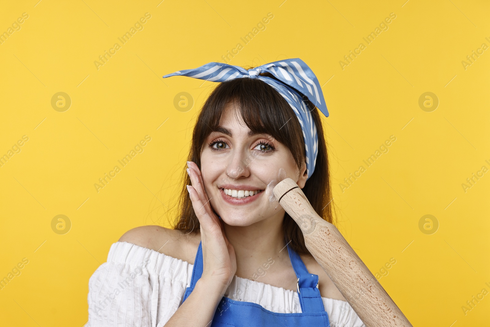 Photo of Happy woman with rolling pin on yellow background