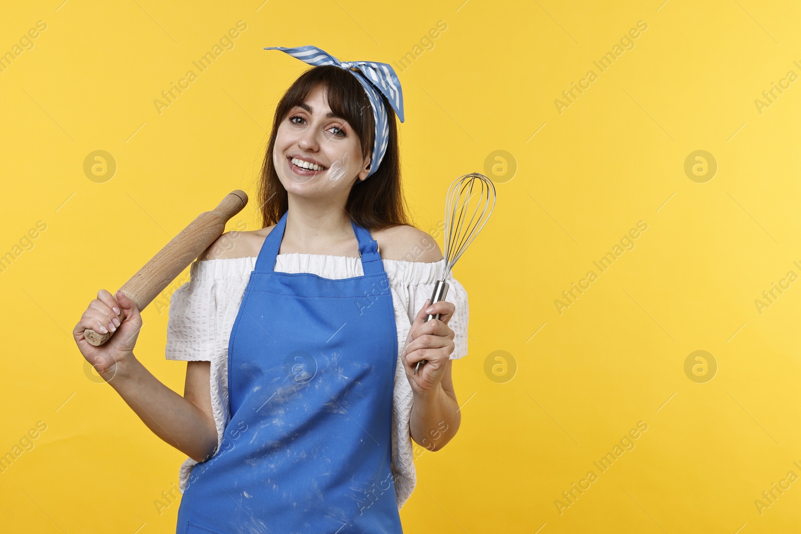 Photo of Woman with rolling pin and whisk on yellow background. Space for text