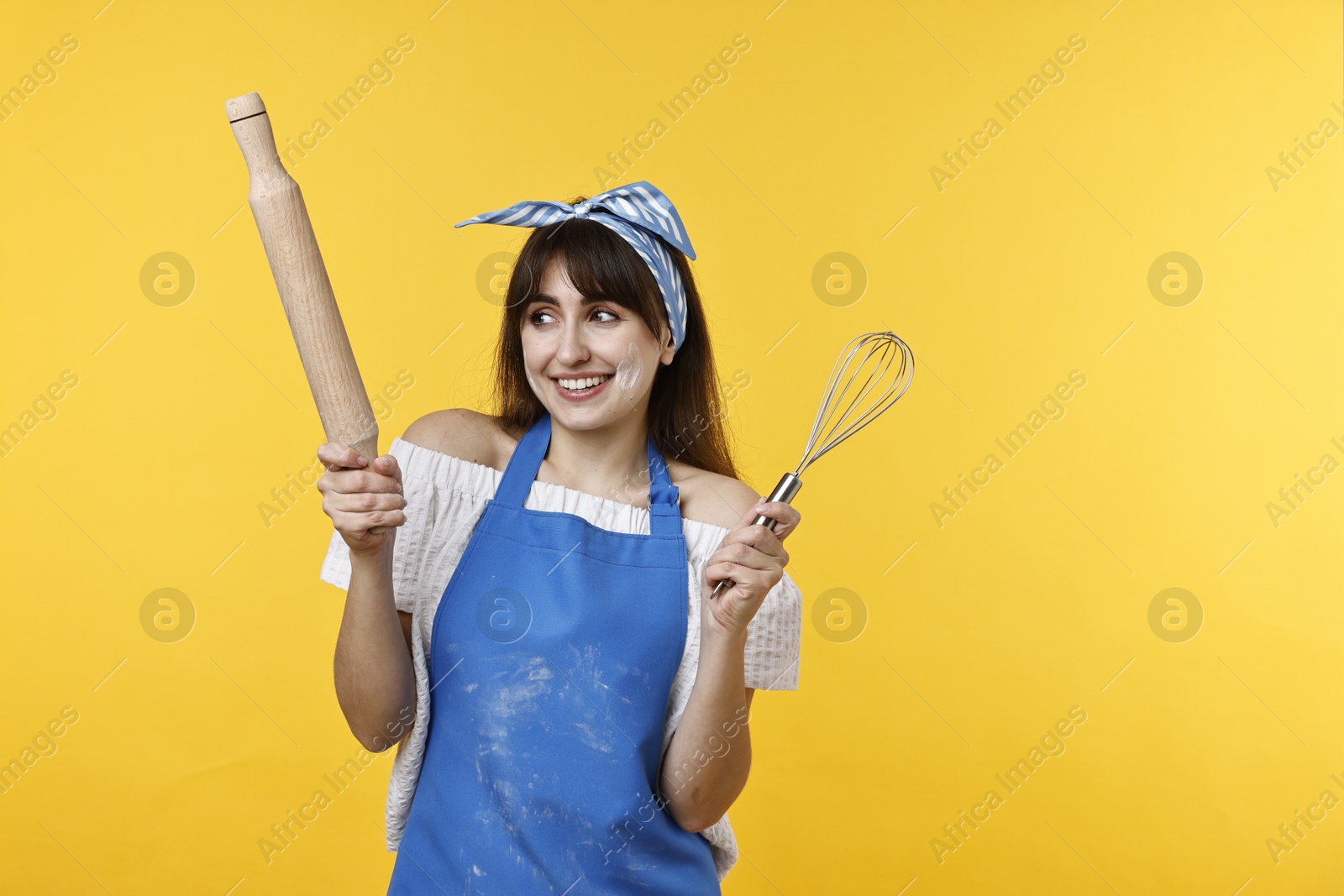 Photo of Woman with rolling pin and whisk on yellow background. Space for text