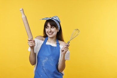 Photo of Woman with rolling pin and whisk on yellow background. Space for text